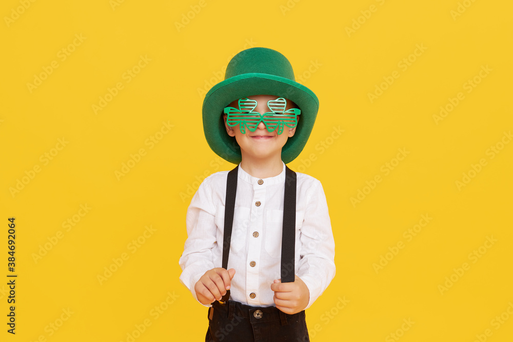 Smiling little child boy in green leprechaun hat on yellow background. St. Patrick Day celebration. Funny face Smiling little child boy in green leprechaun hat on yellow background. St. Patrick Day celebration. Funny face