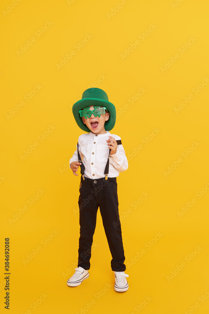 Smiling little child boy in green leprechaun hat on yellow background. St. Patrick Day celebration. Funny face Smiling little child boy in green leprechaun hat on yellow background. St. Patrick Day celebration. Funny face