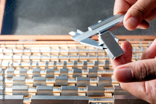 The inspector is calibrating a vernier caliper micrometer with a gauge block. A small number of gauge blocks can be used to create accurate lengths within a wide range.