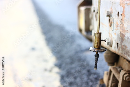 close up stainless steel spike measure the thickness of asphalt road between making hanging on asphalt paver machine