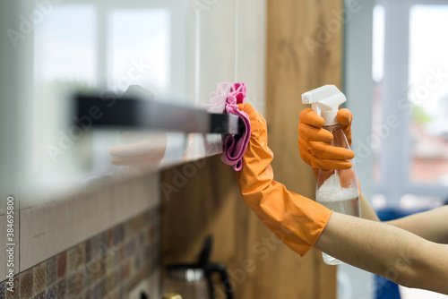woman in rubber gloves and cleaning the kitchen counter with sponge