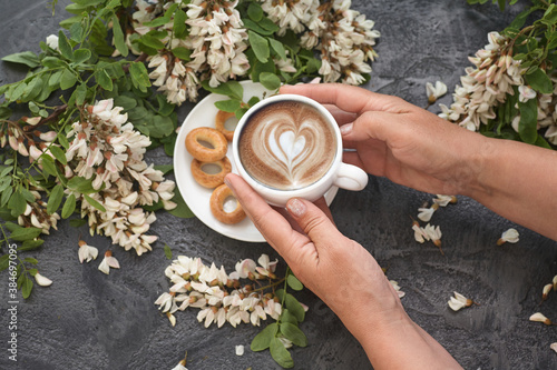 Spring layout with Coffee in female hands and white acacia flowers. photo