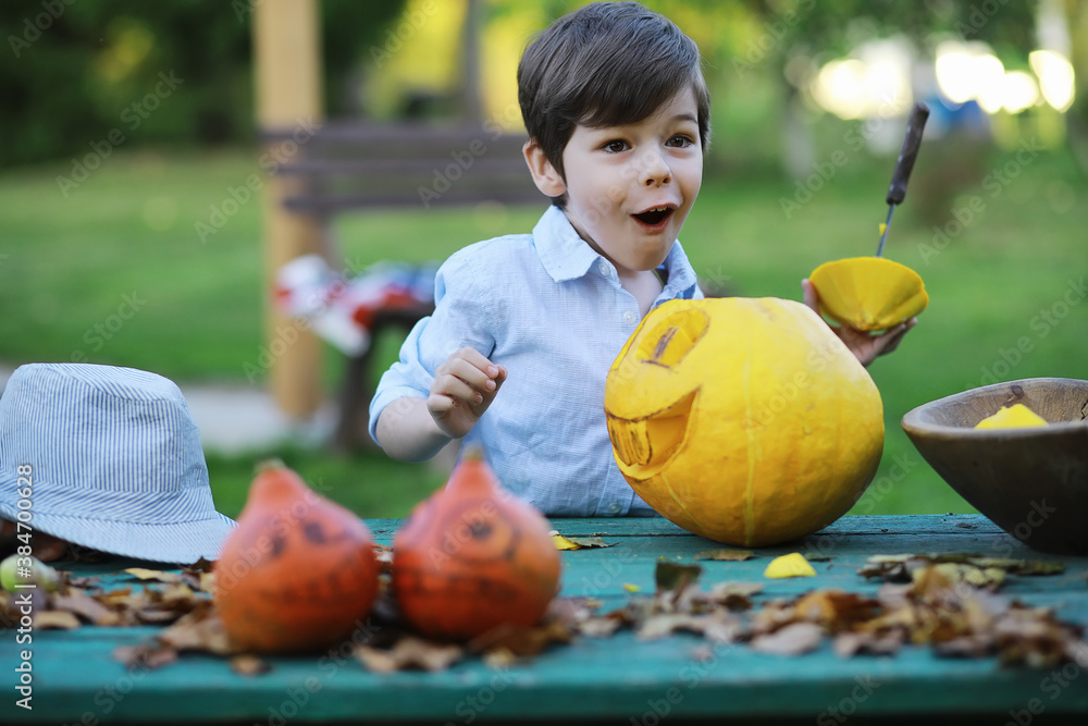 Fototapeta premium Autumn traditions and preparations for the holiday Halloween. A house in nature, a lamp made of pumpkins is cutting out at the table.