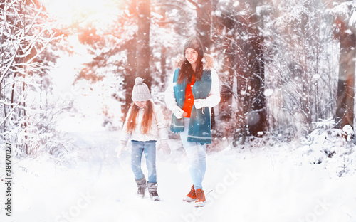 Young family for a walk. Mom and daughter are walking in a winter park. © alexkich