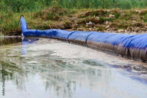 Oil spill. A floating barrier used to contain an oil spill. Environmental disaster.