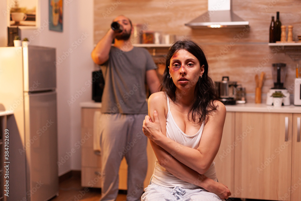 Traumatised woman in kitchen after being violent bruised by agressive husband. Man abusing injuring terrified helpless, vulnerable, afraid, beaten and panicked wife living in terror and pressure Traumatised woman in kitchen after being violent bruised by agressive husband. Man abusing injuring terrified helpless, vulnerable, afraid, beaten and panicked wife living in terror and pressure