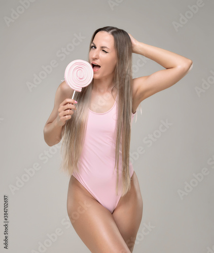 Beautiful slim and fit girl with long blond hair in pink swimsuit. Glowing skin