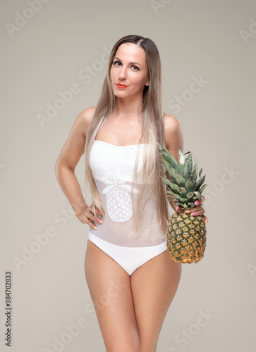 Beautiful slim and fit girl with long blond hair in white swimsuit. Glowing skin