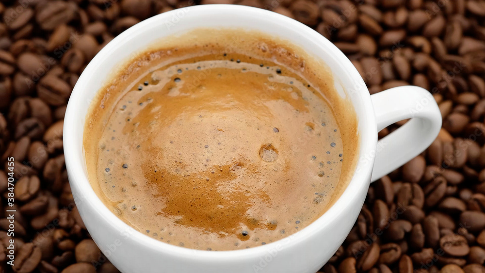 a cup of black coffee with froth on coffee beans top view a cup of black coffee with froth on coffee beans top view