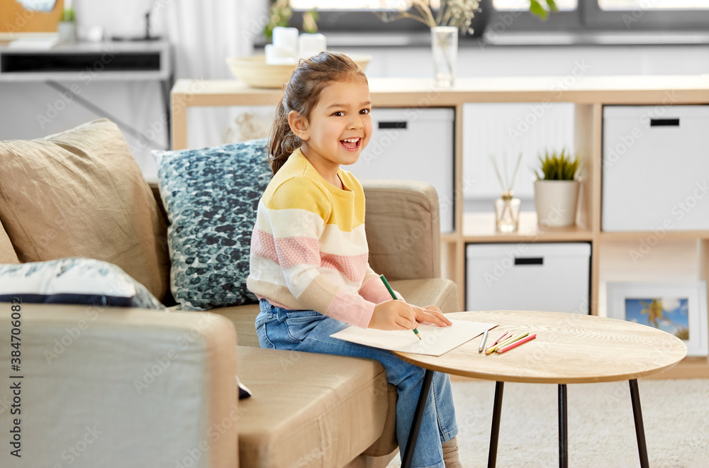 childhood, creativity and art concept - happy smiling little girl drawing with coloring pencils at home