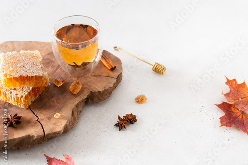 Strengthening immunity in autumn. Hot tea in a glass cup, honey combs and spieces on a wooden tray on white background. Copy space, produst place. Flu, covid-19 treatment