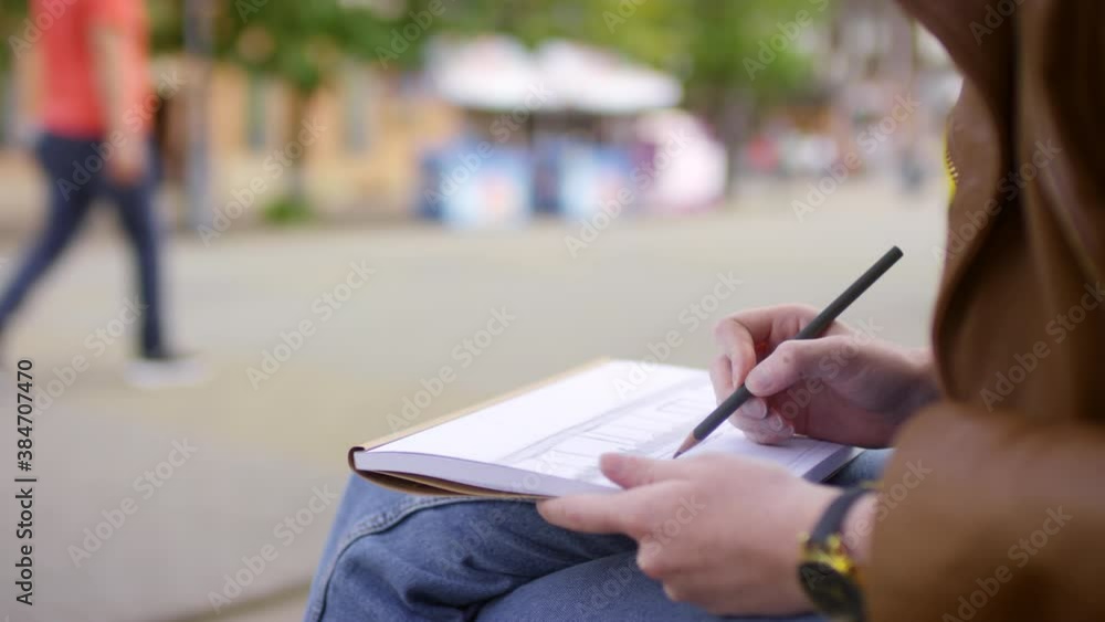 Tracking with mid-section of hands of unrecognizable young girl sitting outdoors and sketching in notebookTracking with mid-section of hands of unrecognizable young girl sitting outdoors and sketching Tracking with mid-section of hands of unrecognizable young girl sitting outdoors and sketching in notebookTracking with mid-section of hands of unrecognizable young girl sitting outdoors and sketching