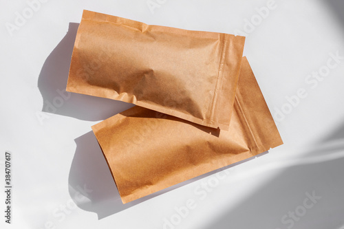 Brown kraft paper pouch bags with coffee beans top view with shadow isolated on white background. Packaging for foods and goods template mockup. Pack with clasp for tea leaves,weight products flat lay