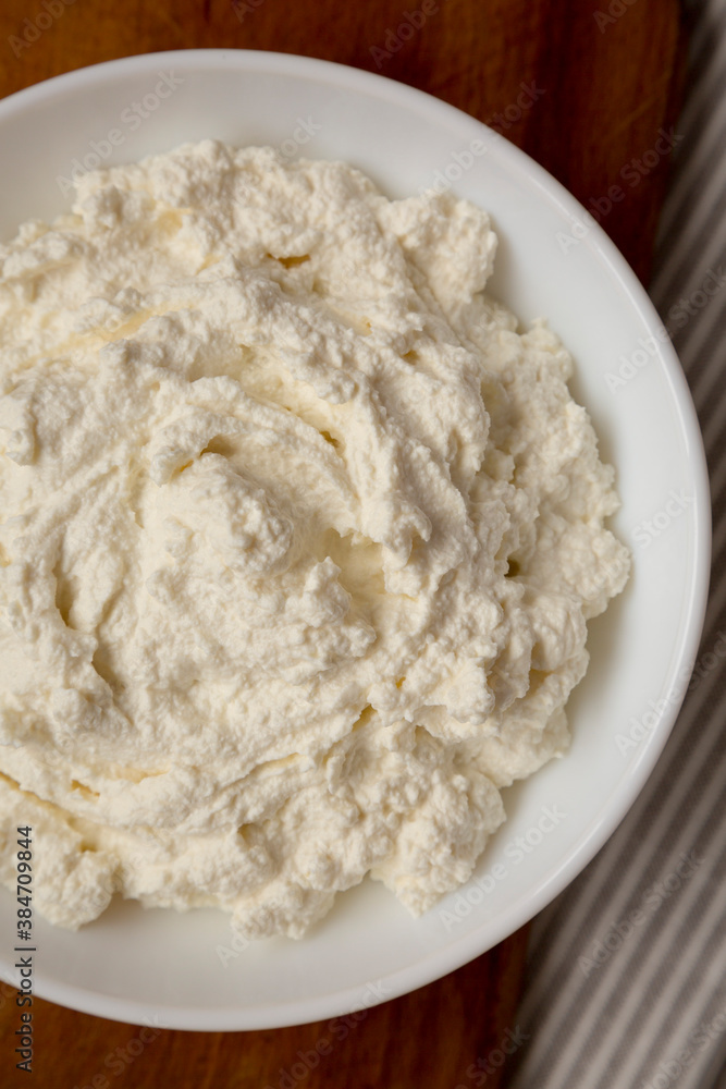 Tasty Ricotta Cheese in a white bowl, top view. Overhead, from above, flat lay.
