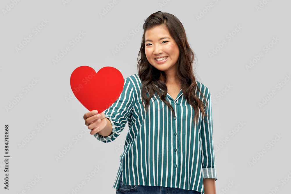 love, charity and valentines day concept - happy asian young woman with red heart over grey background love, charity and valentines day concept - happy asian young woman with red heart over grey background