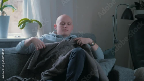 Man getting cozy in the sofa with a blanket. photo