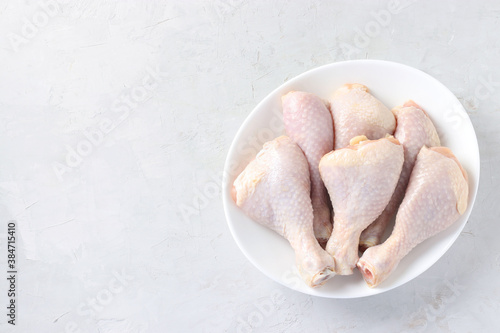 Raw chicken drumsticks in white plate on light gray background, Top view, Horizontal format, Space for text