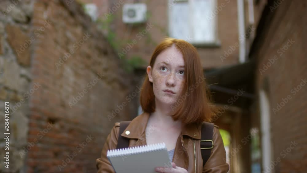 Tracking with low angle of creative female art student sitting in alleyway and sketching buildings Tracking with low angle of creative female art student sitting in alleyway and sketching buildings