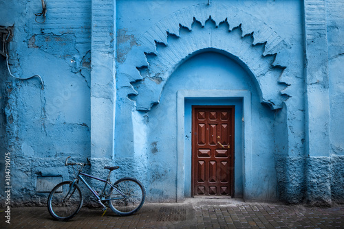 Traditional Moroccan ancient wooden entry door. In the old Medina in Chefchaouen, Morocco. Typical, old, blue intricately carved, studded, Moroccan riad door. © mitzo_bs