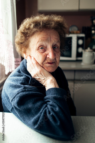 Portrait of old woman in the kitchen at rural home.