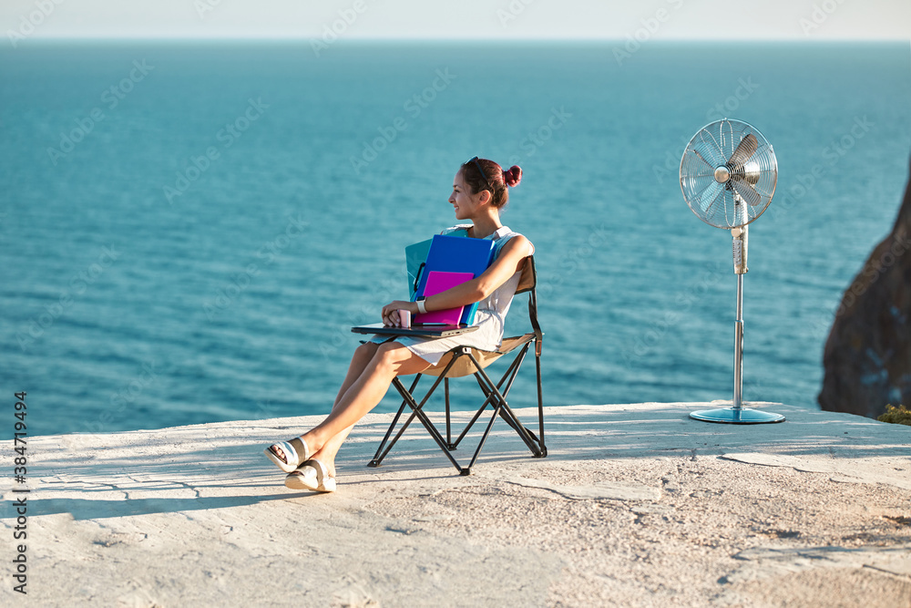 Remote work, freelance concept. Lifestyle change idea. Smiling woman sitting on tourist chair with documents and laptop