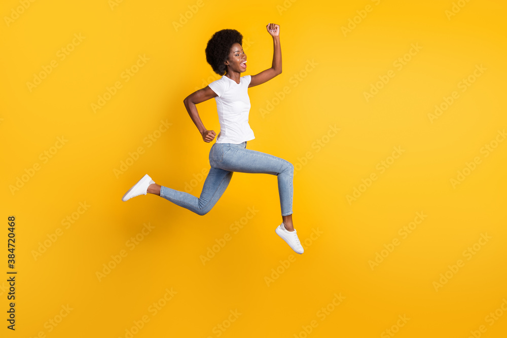 Full length body size photo of funny pretty female hipster with black skin jumping high running fast screaming loudly isolated on bright yellow color background Full length body size photo of funny pretty female hipster with black skin jumping high running fast screaming loudly isolated on bright yellow color background