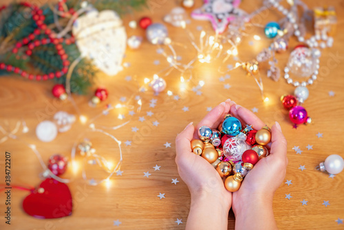 Christmas concept. Human hands hold a glass christmas baubles with festive lights and xmas ornaments on background