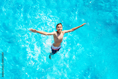 View from above of the boy falls in the water stretch hands jump diving in pool