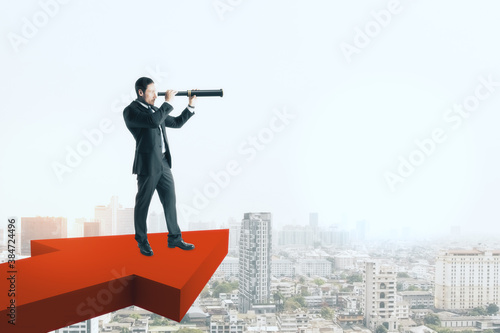Businessman standing on red arrow and using binoculars