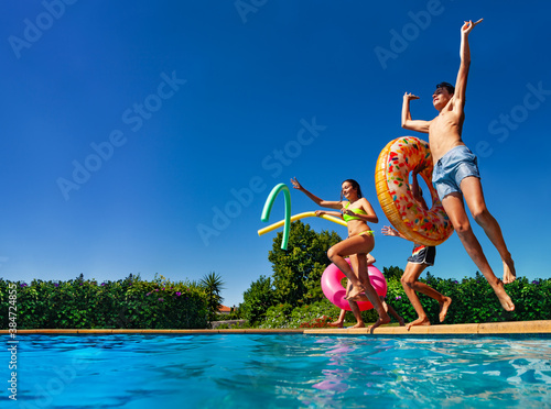 Many of happy teenage kids dive in the swimming pool water throw inflatable toys lifting hands have fun © Sergey Novikov