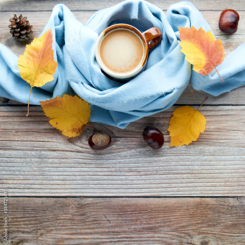 Autumn leaves, cup of coffee and warm scarf on wooden table. Fall season, leisure time, Sunday relaxing, coffee break and still life concept. Selective focus. Top view, copy space.