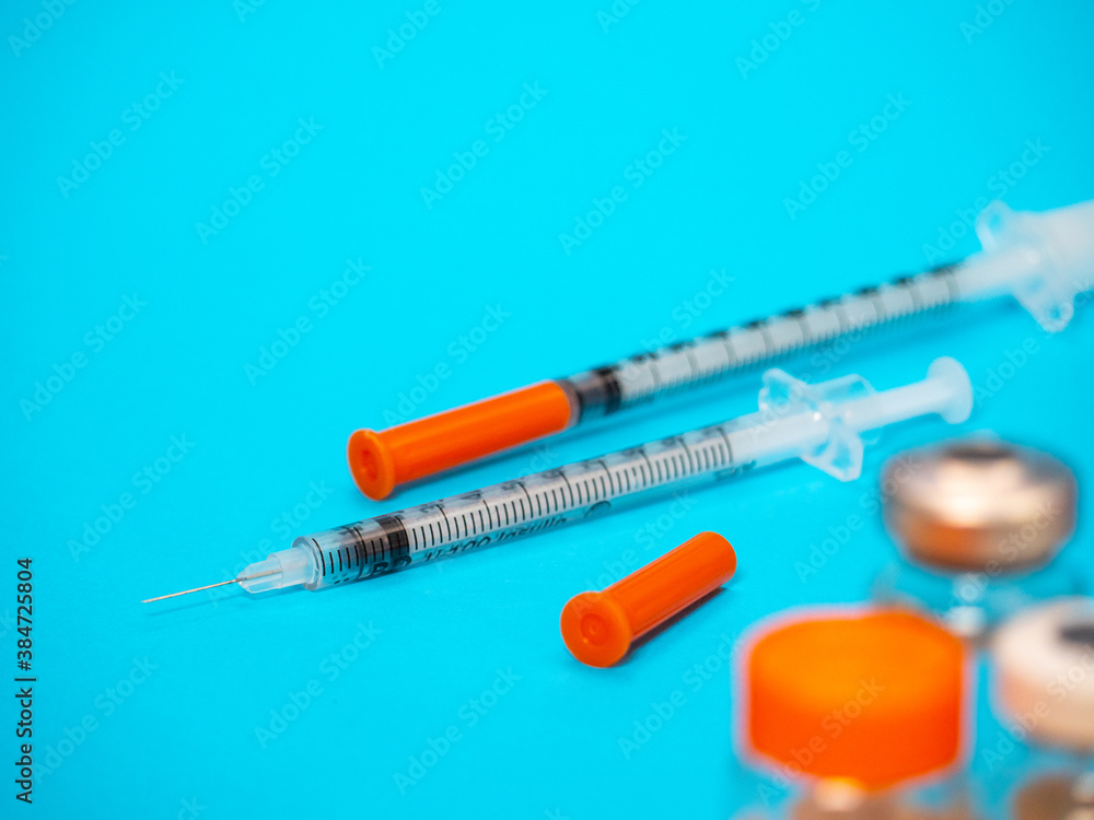 Insulin vial and syringe on blue background. Health care, doctor, clinic or hospital, medical concept. World diabetes day. Ready for vaccine injection. Pain treatment, illegal use, vaccination Insulin vial and syringe on blue background. Health care, doctor, clinic or hospital, medical concept. World diabetes day. Ready for vaccine injection. Pain treatment, illegal use, vaccination