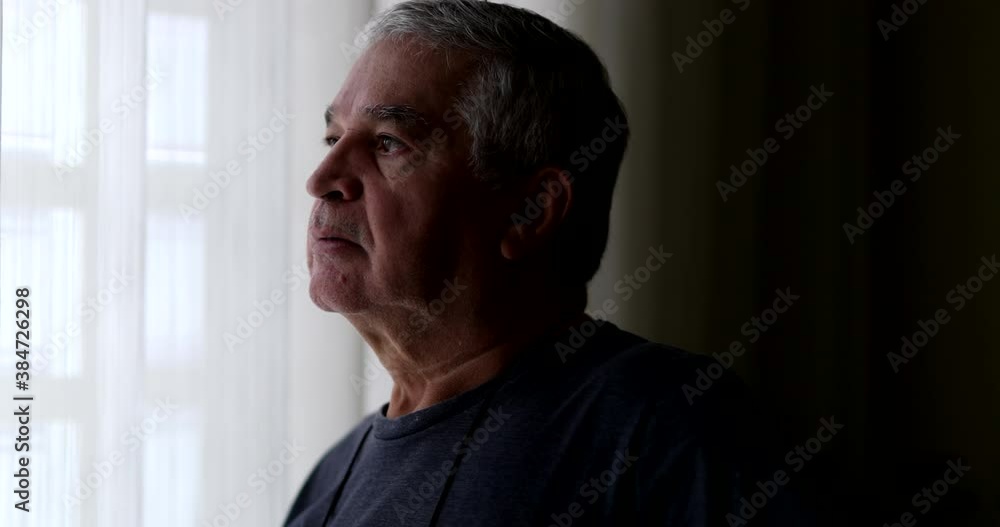 Contemplative senior looking through window. Pensive thoughtful older man Contemplative senior looking through window. Pensive thoughtful older man