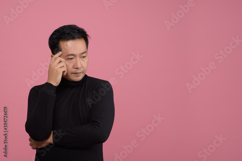 Portrait of asian middle man thoughtful  wearing black sweater  in casual style thinking. Studio shot on pink background. © vipubadee