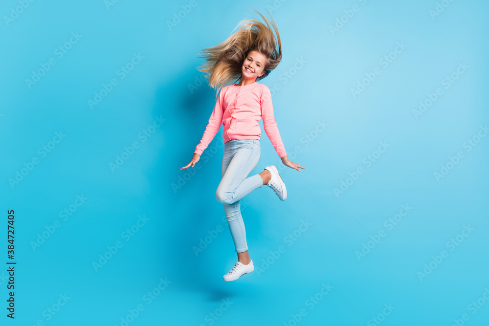 Photo portrait of girl jumping up waving hair isolated on pastel blue colored background