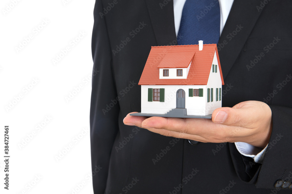A person in formal wear holds a small house model in his hand A person in formal wear holds a small house model in his hand