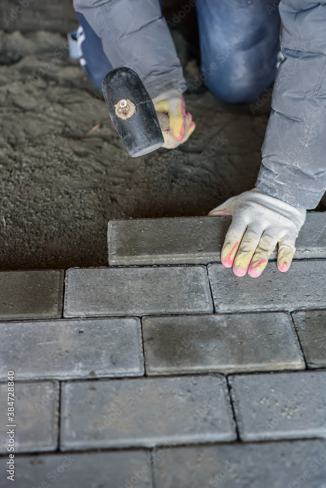Man laying paving stones on the floor using a rubber mallet. Vertical Man laying paving stones on the floor using a rubber mallet. Vertical