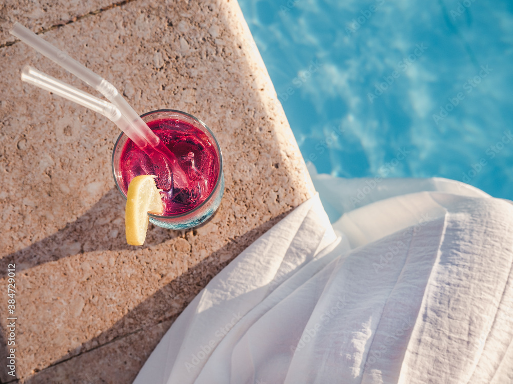 Beautiful cocktail glass on the background of the pool. View from above, close-up. Concept of leisure and travel