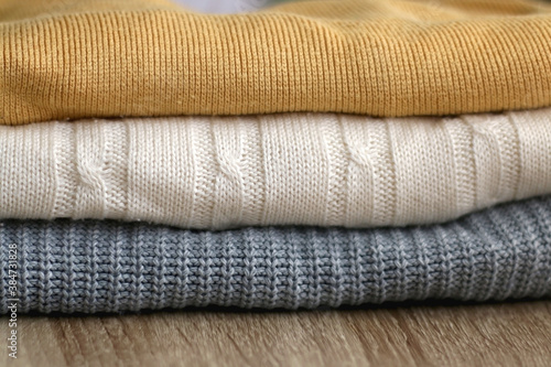 Stack of sweaters on wooden table. Selective focus.