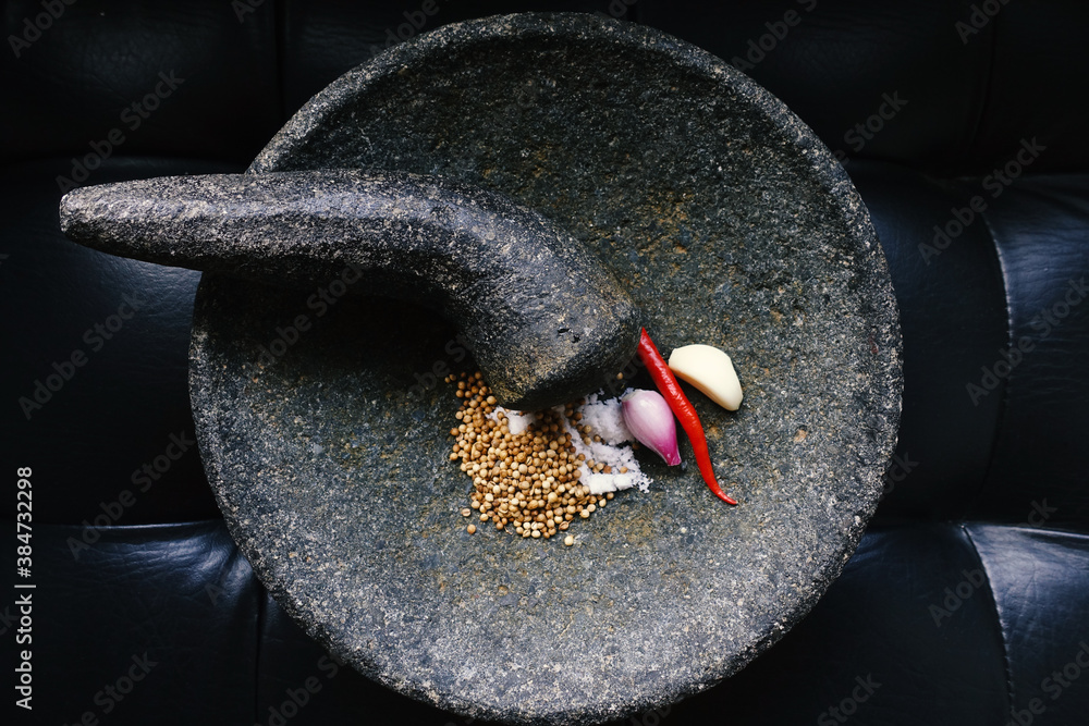 Stockfoto Indonesian traditional spices on stone mortar, traditional tools or grinder made of stone called 'coet' or 'cobek' | Adobe Stock