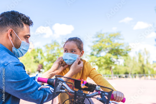 Father Putting Mask on to his Daughter for Coronavirus Protection .