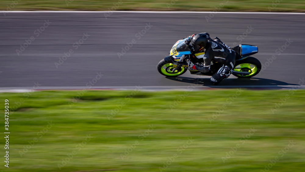 A panning shot of a racing bike cornering as it circuits a track.