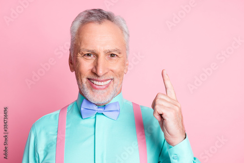 Photo portrait of cheerful smiling elder man with white beard keeping finger up isolated on pink color background with blank space