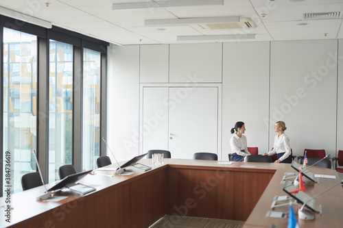 Wide angle shot of classic conference room interior with two female secretaries in background  copy space