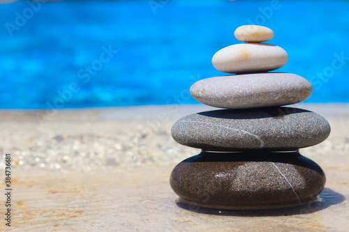 Zen concept. Stack of stones near the pool with copy space. Blurred background. Concept of harmony, stability, life balance, and meditation