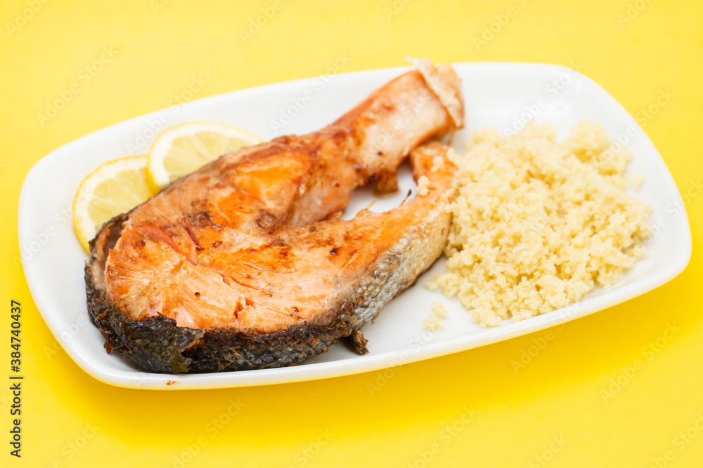 fried salmon with cous cous and lemon on white dish fried salmon with cous cous and lemon on white dish