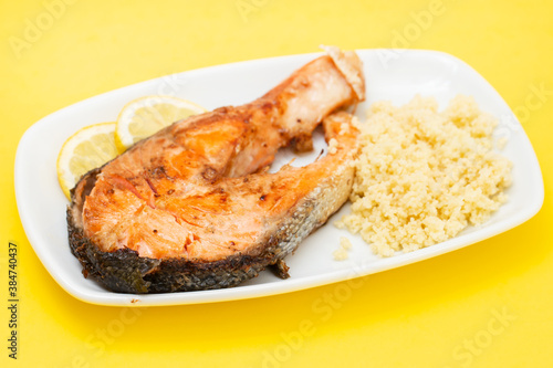 fried salmon with cous cous and lemon on white dish
