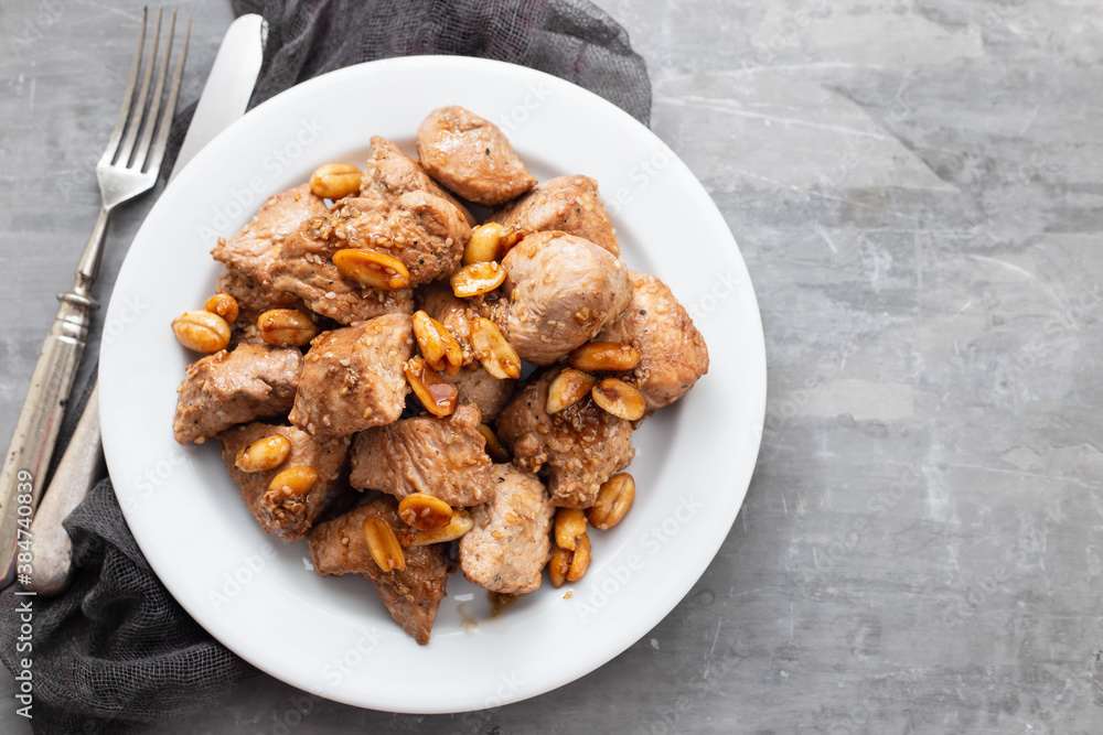 meat with nuts on white plate on ceramic background meat with nuts on white plate on ceramic background