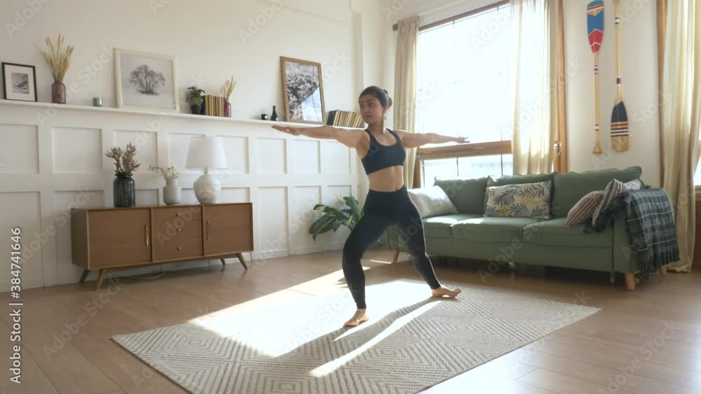 Woman in Leggings and T-shirt Doing Yoga Poses in Living Room on Sunny Morning Woman in Leggings and T-shirt Doing Yoga Poses in Living Room on Sunny Morning