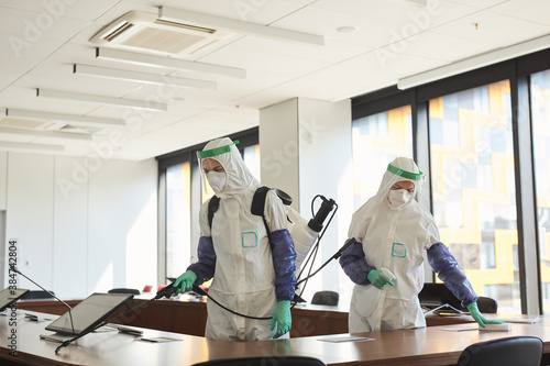 Photography Wide angle portrait of two sanitation workers wearing hazmat suits cleaning and